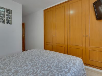 Bright bedroom featuring a double bed and a built-in wooden wardrobe. Functional, minimalist decor.