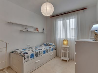 Bright bedroom featuring a single bed, decorative shelves, and nautical accents.
