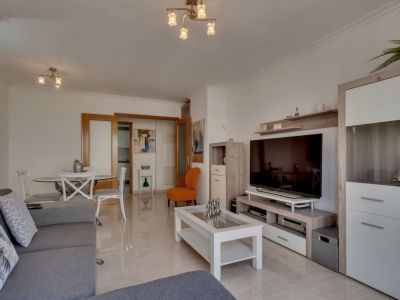 Bright living room featuring tiled floors, a gray sofa, and modern furniture in neutral and white tones.