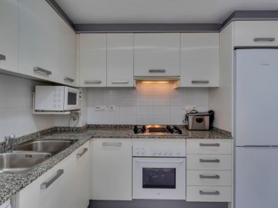 Functional kitchen featuring a granite countertop, white appliances, and warm lighting.