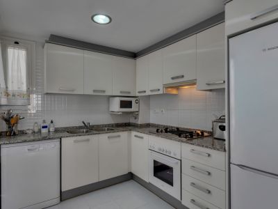 Functional kitchen featuring granite countertops, white appliances, and overhead lighting.