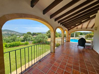 Covered terrace with stone arches overlooking the garden and pool.
