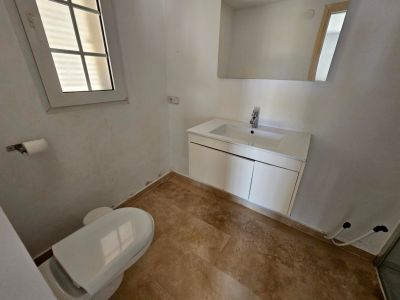 Powder room with a modern vanity and cream-colored tiled floor.