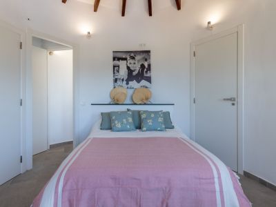 Bright bedroom featuring a double bed, pink bedding, and a headboard decorated with fans.