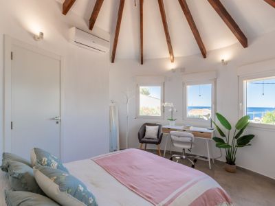 Bright bedroom featuring a vaulted ceiling with wooden beams and a desk with sea views.