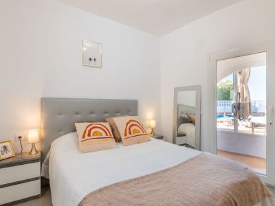 Bright bedroom with gray headboard, white linens, and direct access to the pool area.