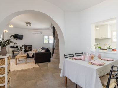 Bright dining room with a set table in pink tones and access to the arched living room.