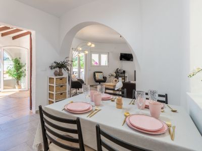 Bright dining room with a table set in pink and gold tones, with access to the terrace and living room.