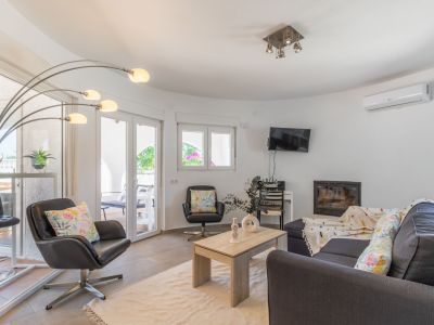 Bright living room featuring a dark gray sofa, leather armchairs, and built-in fireplace.