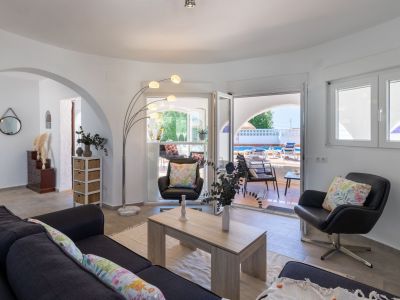 Bright living room with terrace and pool access. Details like the arc lamp and floral cushions enhance the space.