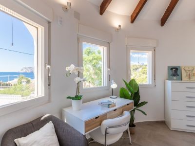 Bright office space with sea views, featuring a modern desk and decorative accents.