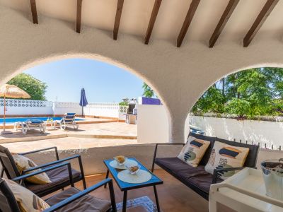Covered porch with pool and garden views, ideal for outdoor relaxation.