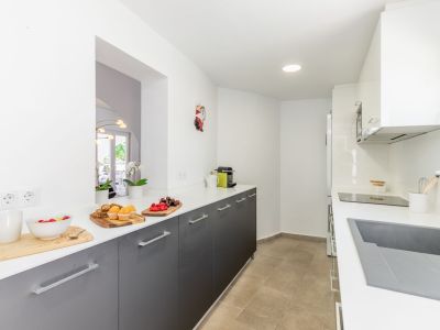 Kitchen detail with white countertop, gray cabinets and ceramic floor. Recessed lighting.