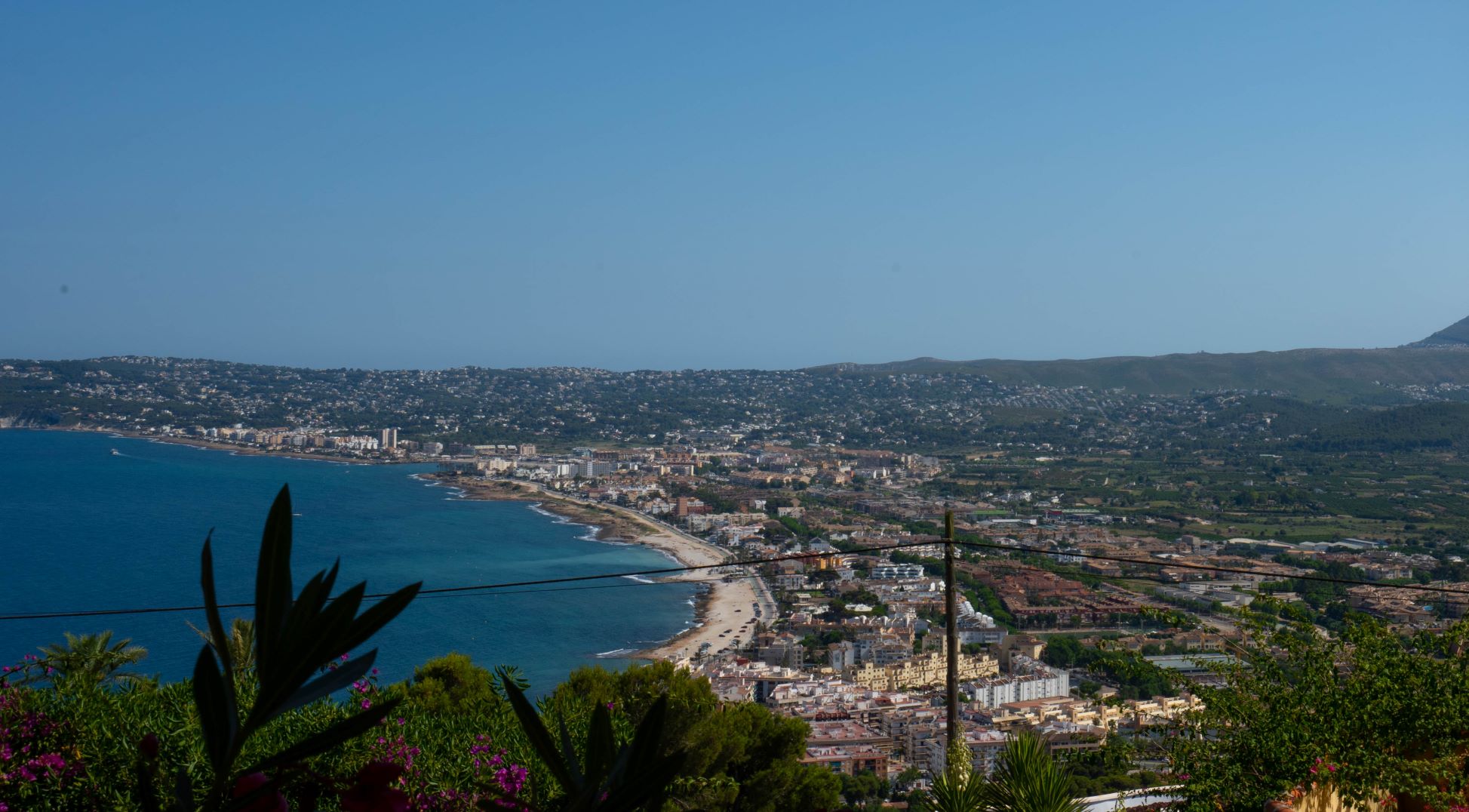 Panoramic view of Jávea Bay from the plot, with vegetation in the foreground.