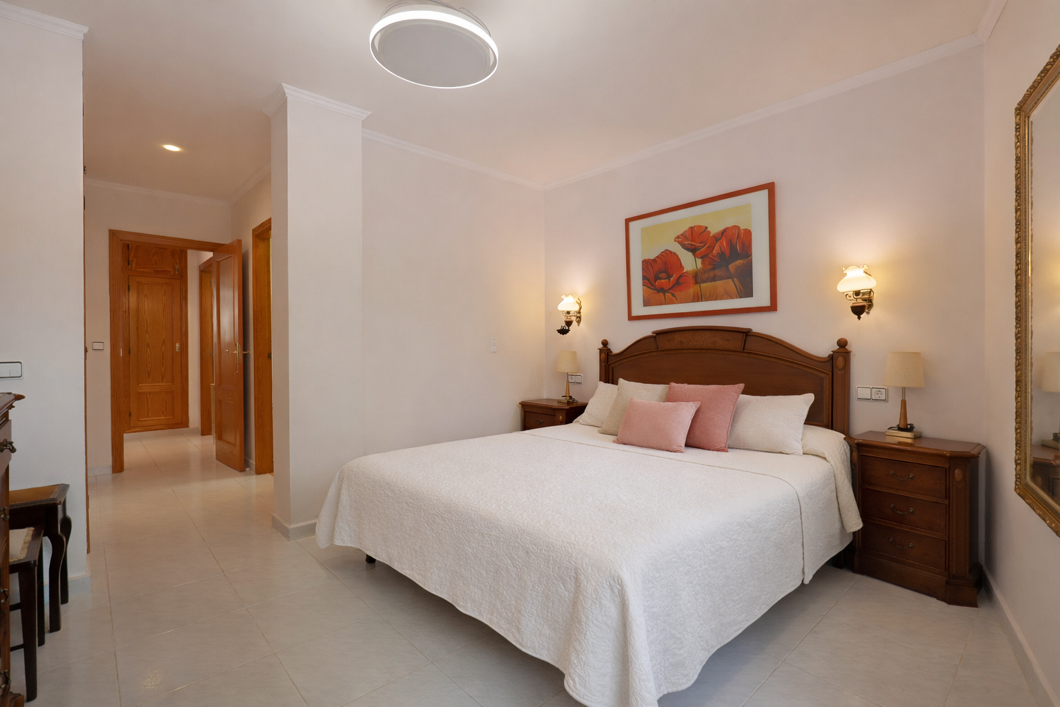 Bright bedroom featuring a double bed, wooden nightstands, and tiled flooring.
