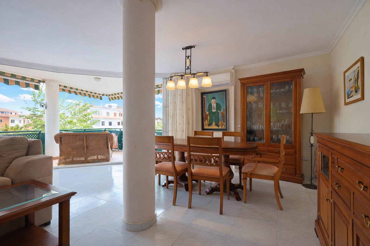 Bright dining area with terrace access, featuring a wooden table and classic display cabinet.