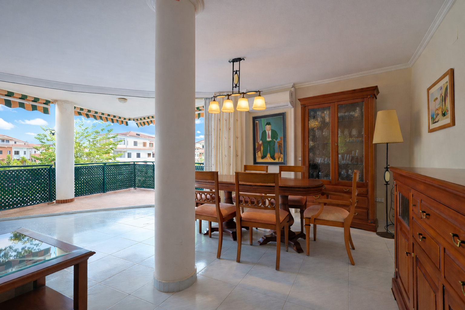 Bright dining room with terrace access, highlighting classic wood furniture and light tile flooring.