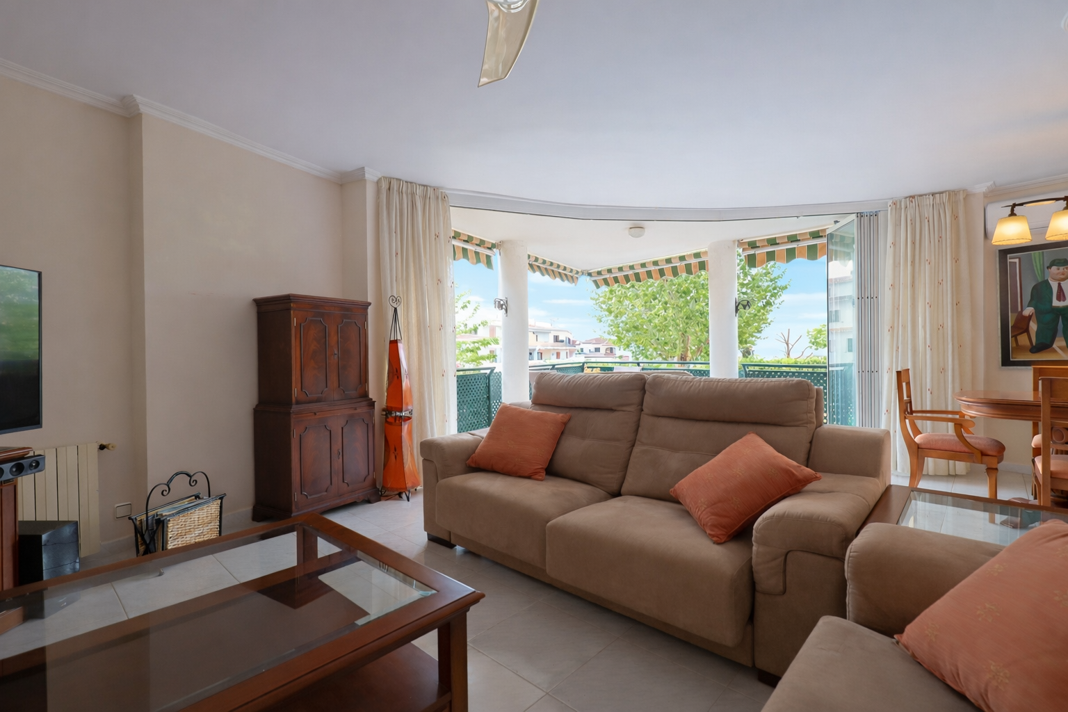 Bright living room with access to a covered terrace, furnished with a beige sofa and a wooden coffee table.