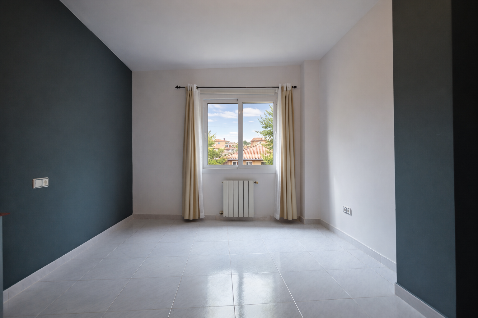 Bright room featuring a lead-blue accent wall, window with a view, and tiled flooring.