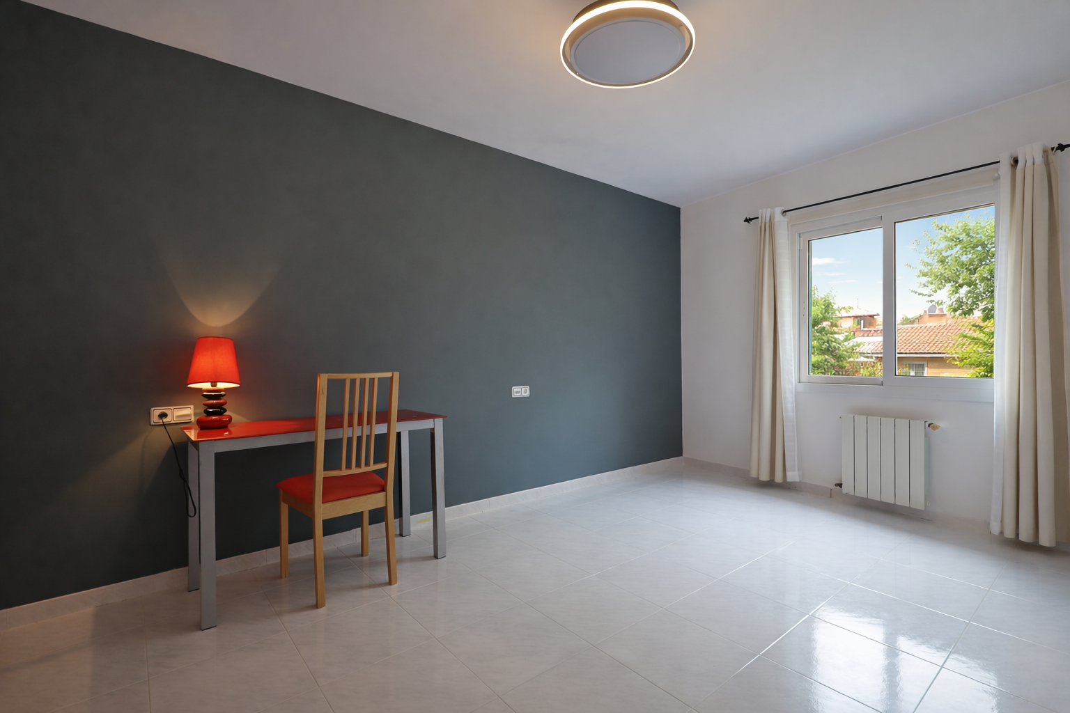 Bright room with red desk and lead gray wall, cream-colored floor tiles, and a circular ceiling light.
