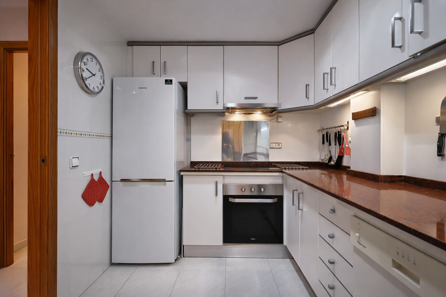 Functional kitchen featuring granite countertops, white appliances, and upper cabinets.