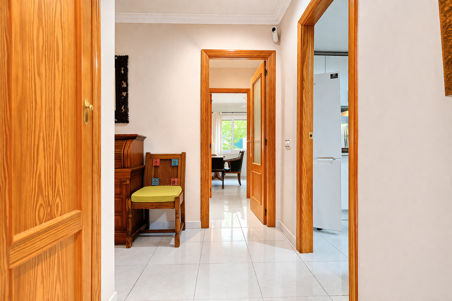 Hallway view with wood door frames and white tile flooring.