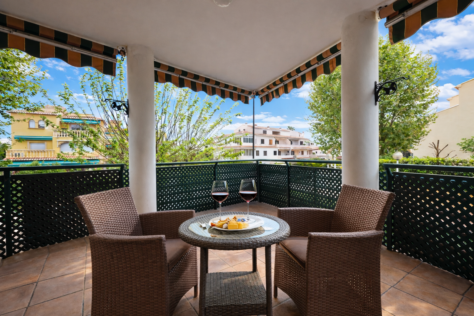 Terrace with striped awning, wicker furniture, and views of residential buildings.