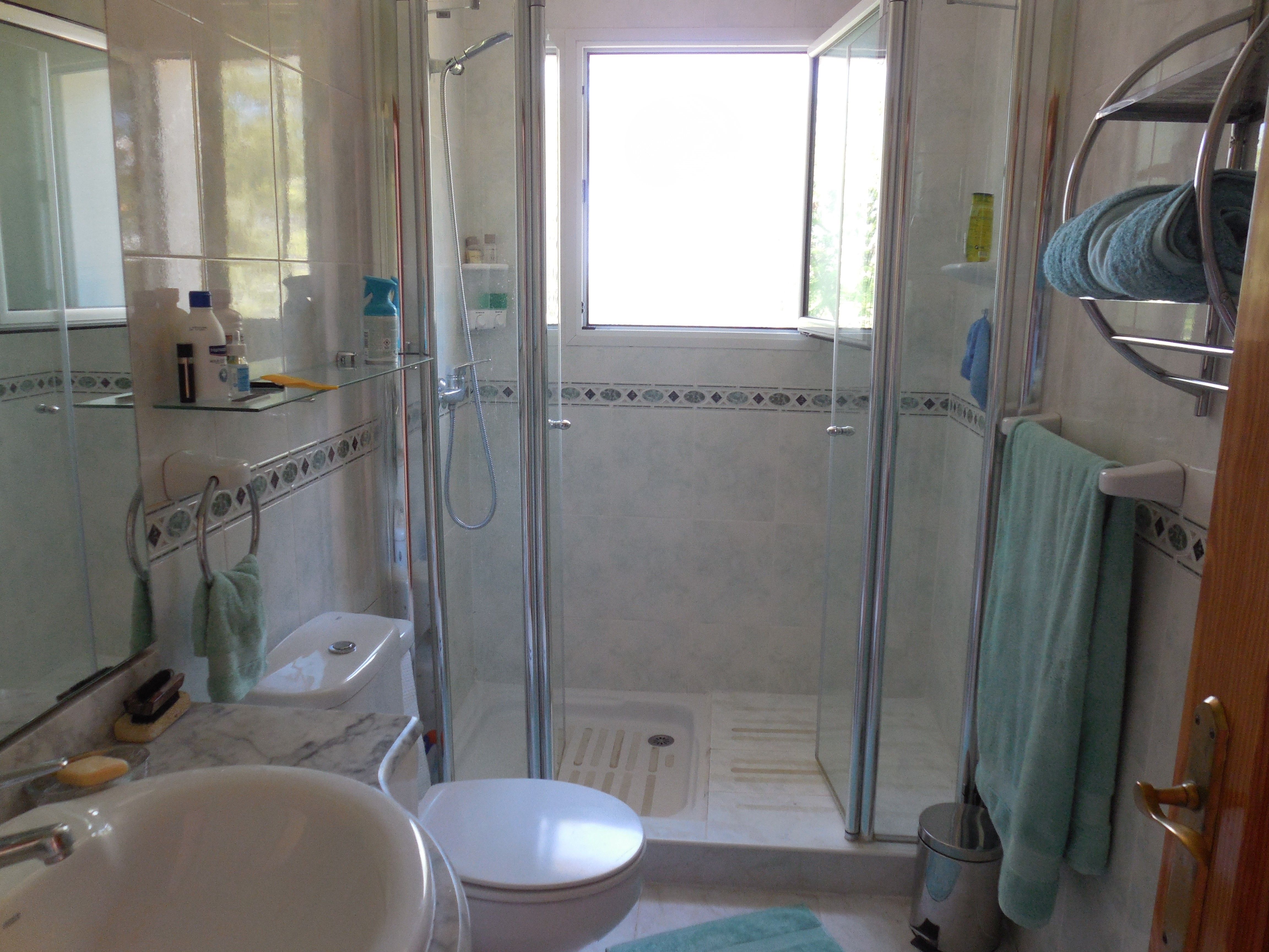 Bathroom featuring glass-enclosed shower, marble-topped sink, and decorative tile accents.
