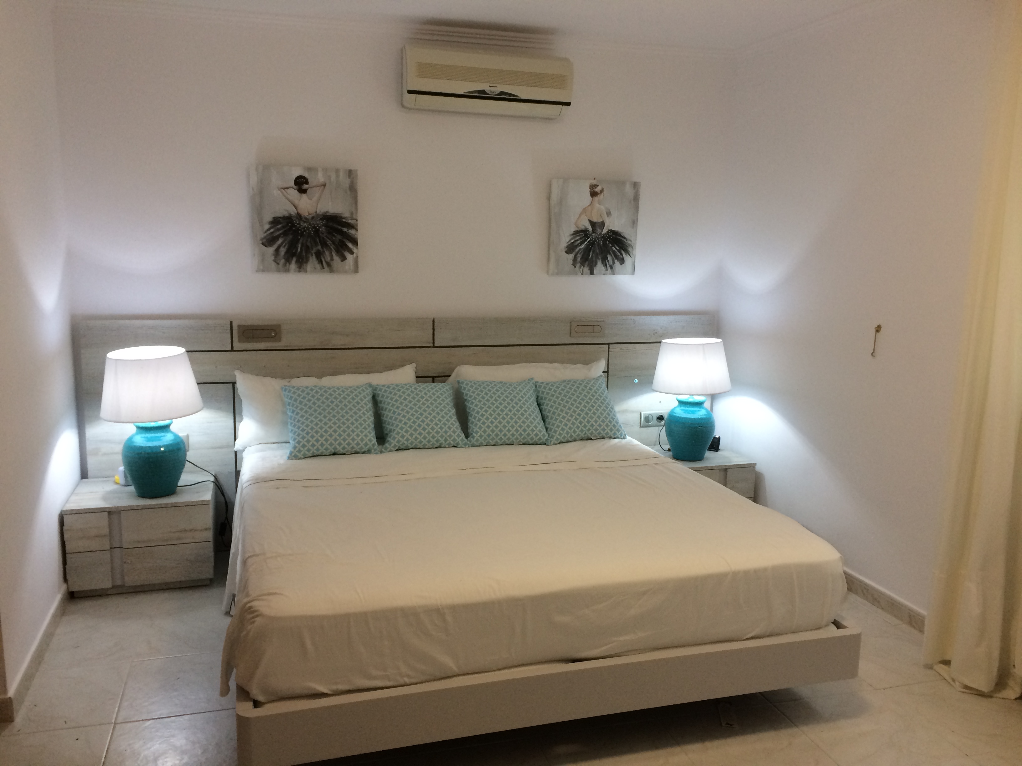 Bedroom featuring a double bed, light wood headboard, and matching nightstands with blue ceramic lamps.