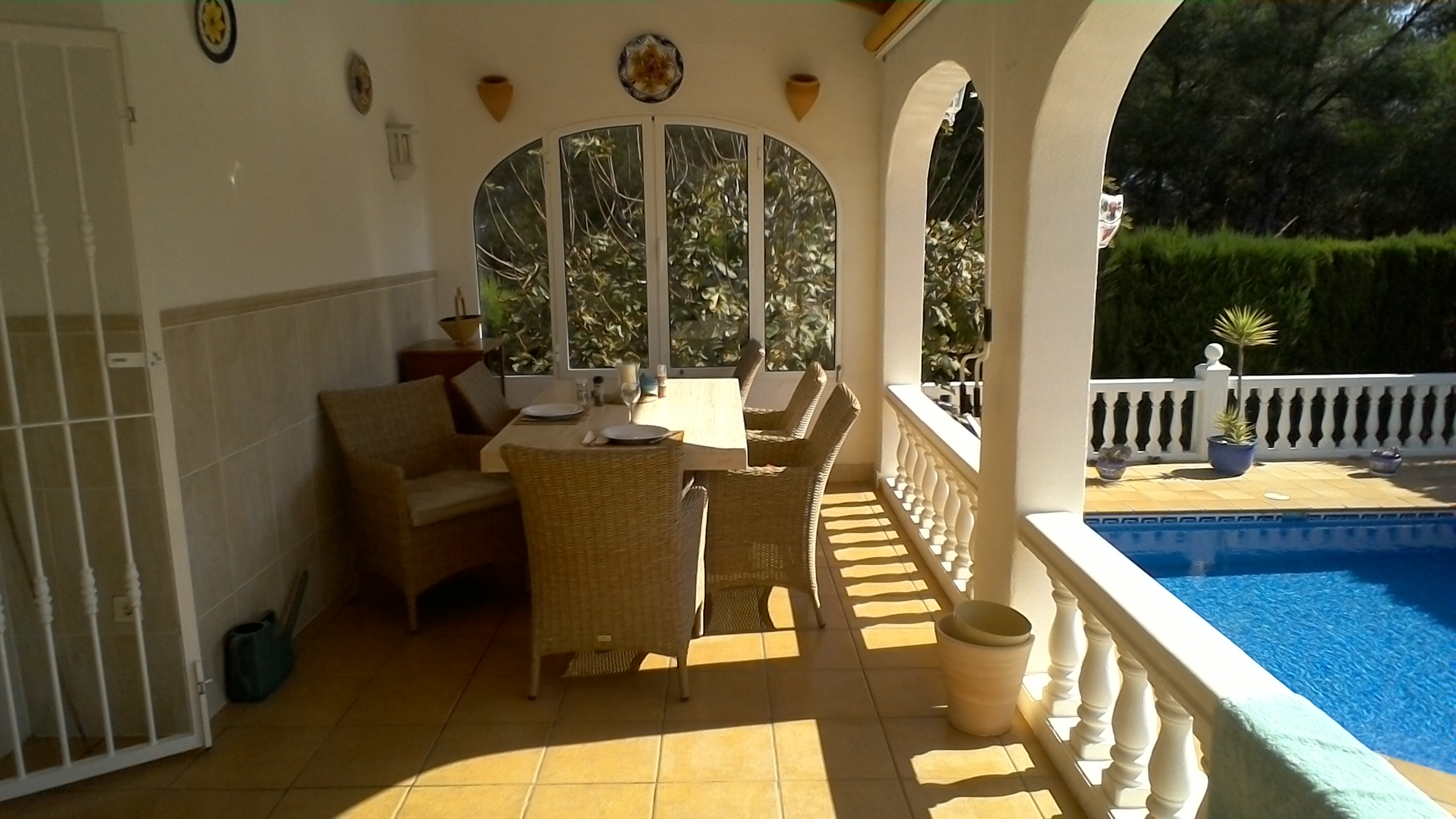 Covered outdoor dining area overlooking the pool and garden.