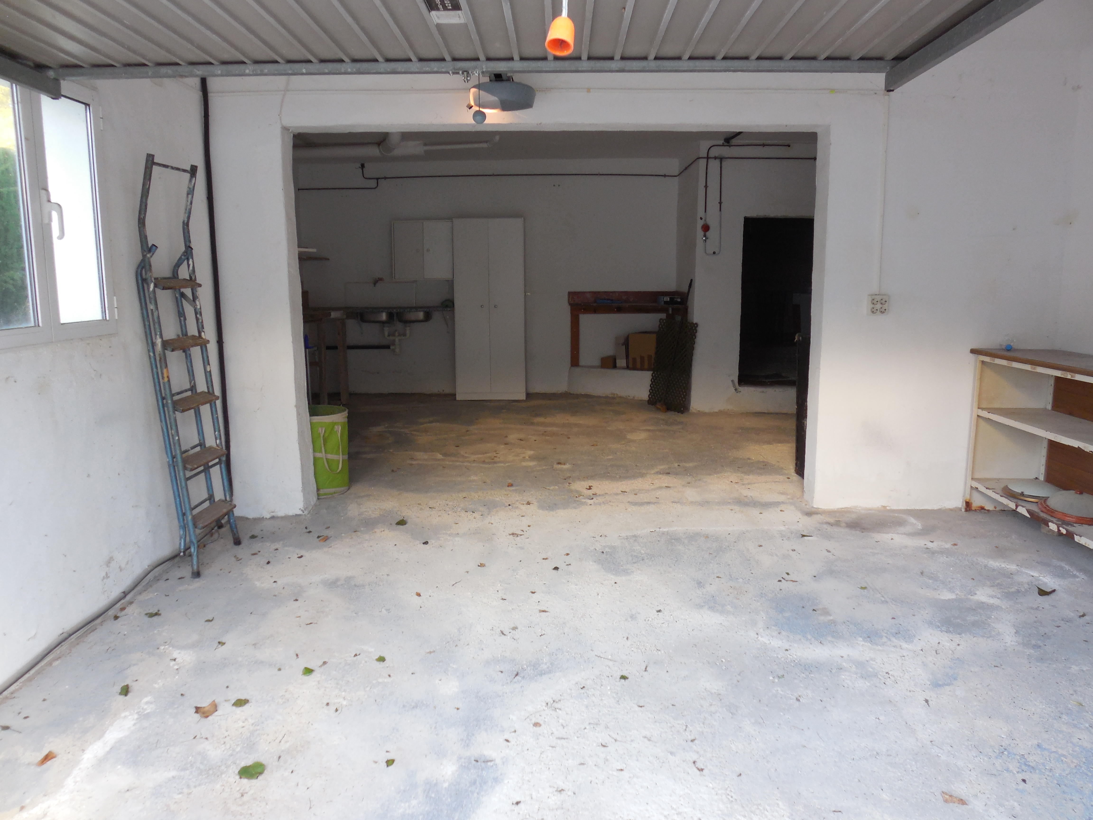 Garage with concrete floor, white walls, and metal shelving.