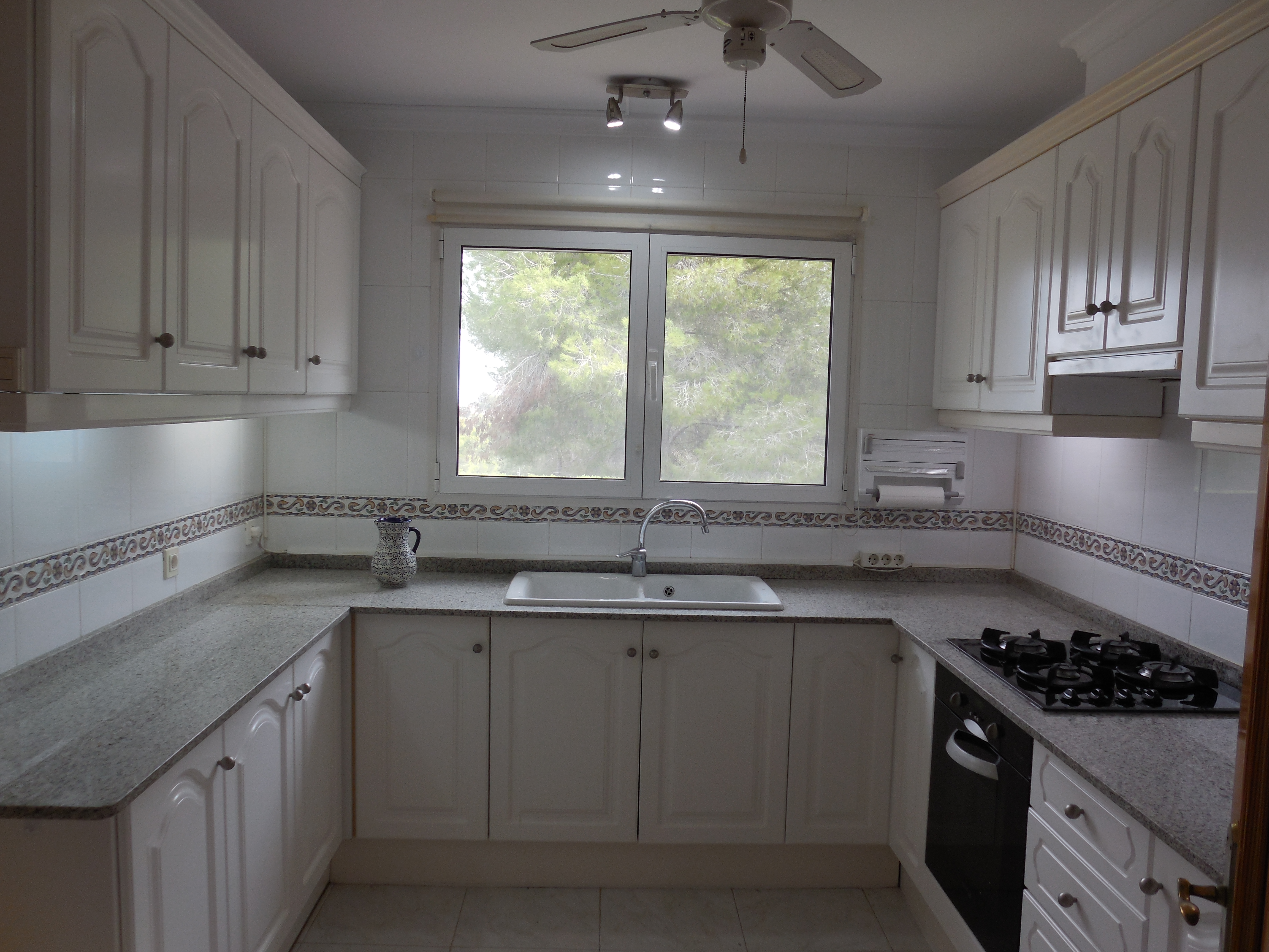 Kitchen with gray granite countertops, classic white cabinets, and a window overlooking the outdoors.
