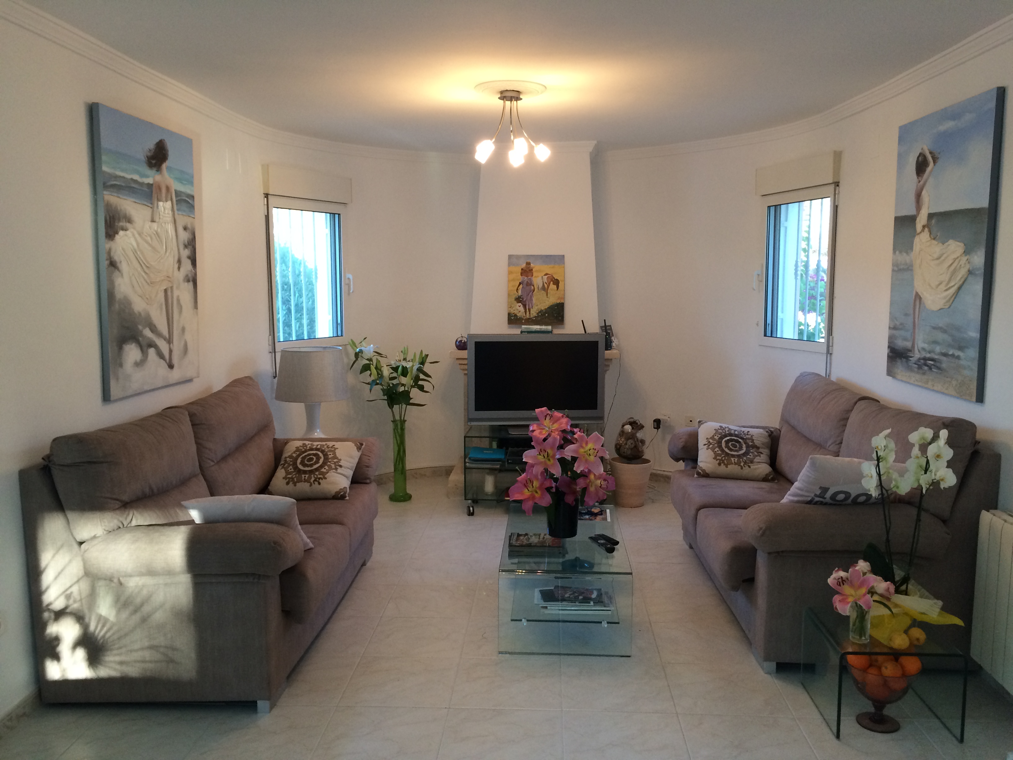 Living room featuring fabric sofas, glass coffee table, and floral decor.