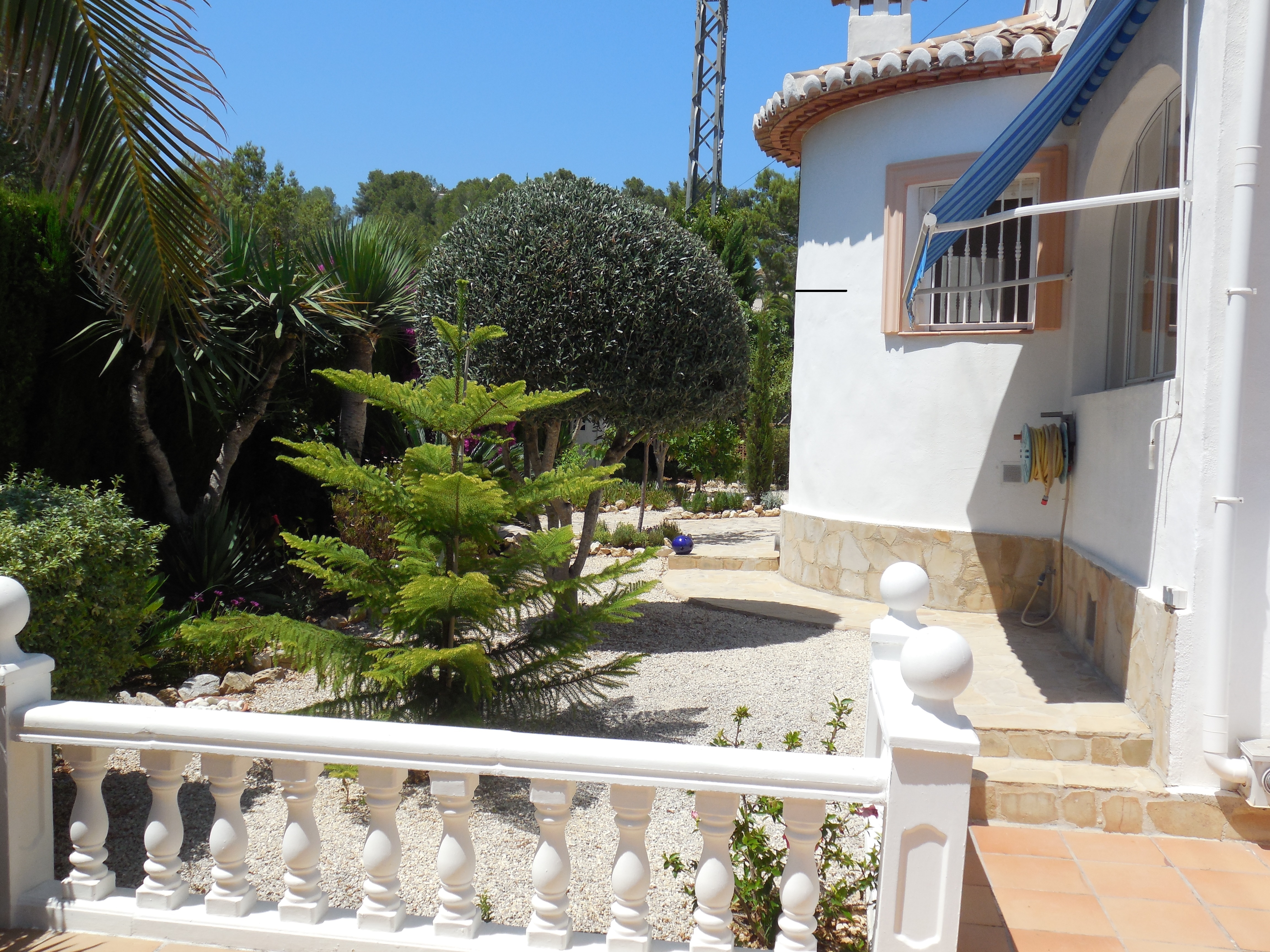 View of the front garden with white gravel and a white balustrade railing.