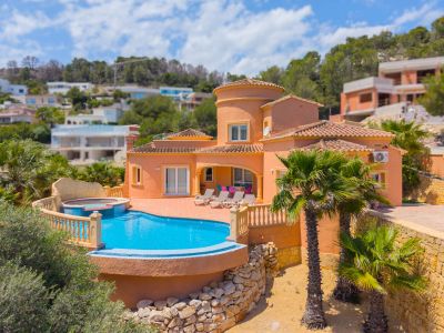 Aerial view of the villa with a turquoise pool and integrated jacuzzi, surrounded by palm trees and gardens.