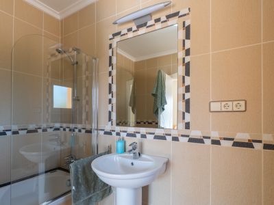 Bathroom detail featuring a pedestal sink and mosaic-framed mirror.