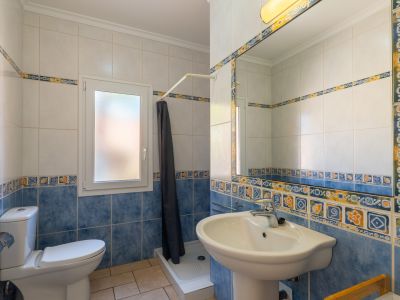 Bathroom detail featuring blue and white decorative tiles, pedestal sink, and a window.