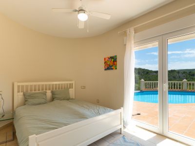 Bright bedroom with direct pool access and a ceiling fan.