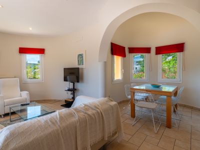 Bright living-dining area featuring tiled floors, an archway, and red curtain accents.