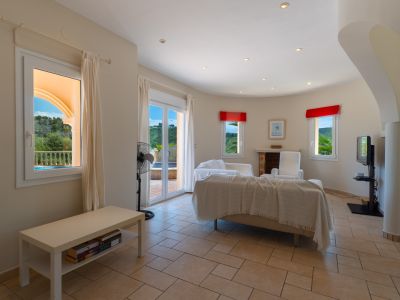 Bright living room featuring tiled floors, a beige sofa with a throw, and outdoor views.