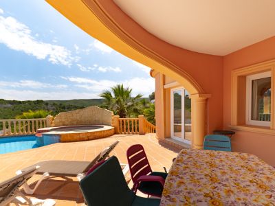 Covered terrace overlooking the pool and jacuzzi. Outdoor furniture and Mediterranean architectural design.