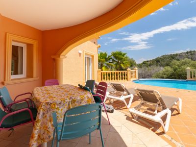 Covered terrace with dining table and pool access in Jávea.