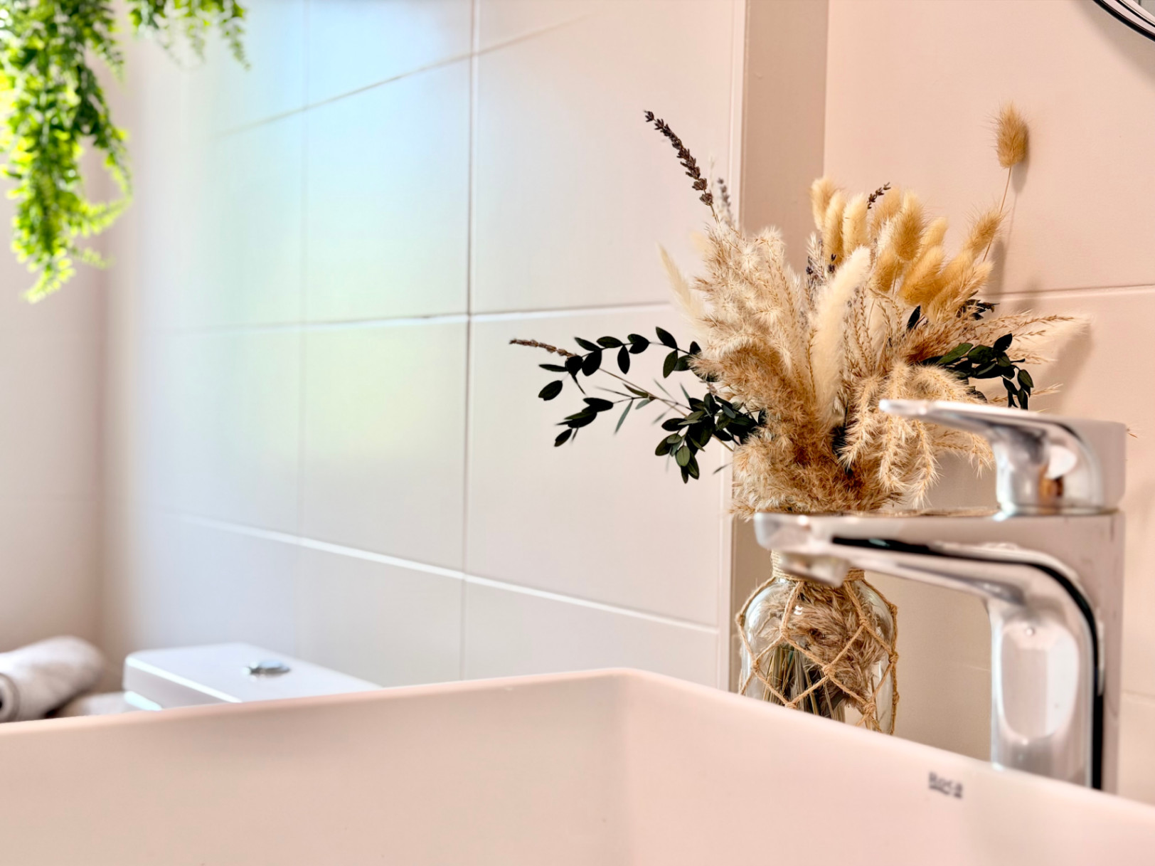 Bathroom detail featuring a white sink, modern faucet, and minimalist floral decor.