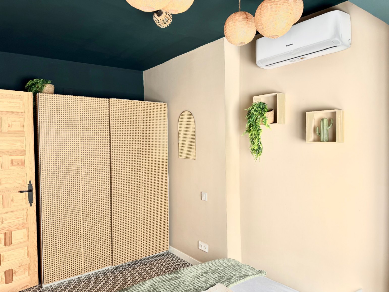 Bedroom with rattan closet, dark green ceiling, and minimalist decor with plants.