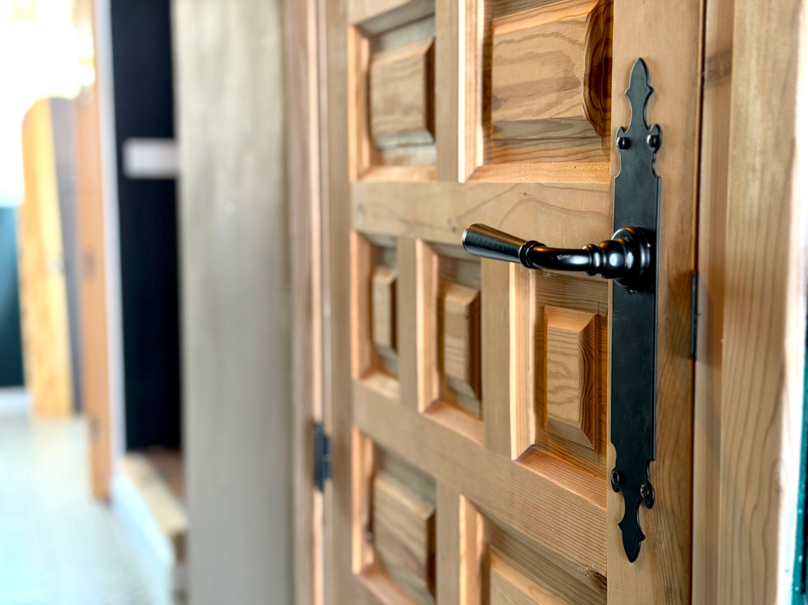 Close-up of a wooden door featuring a raised panel design and wrought iron hardware.