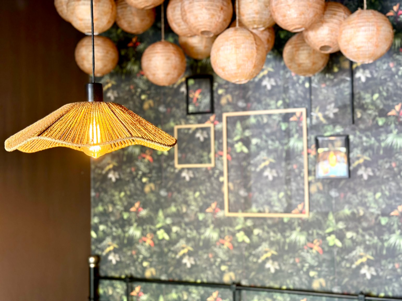 Close-up of the lighting with wicker lamps and floral wallpaper in the room.