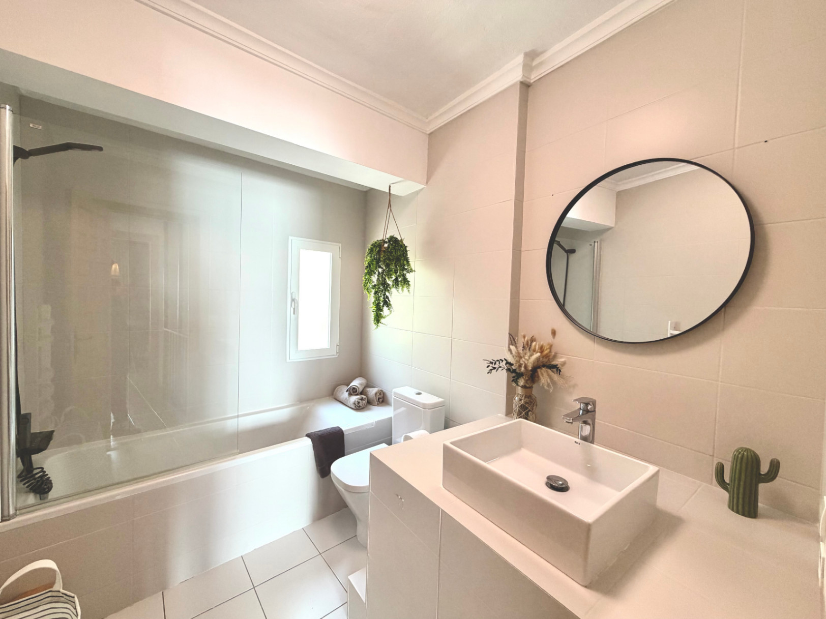 Detail of the renovated bathroom featuring a bathtub, modern sink, circular mirror, and decorative touches.