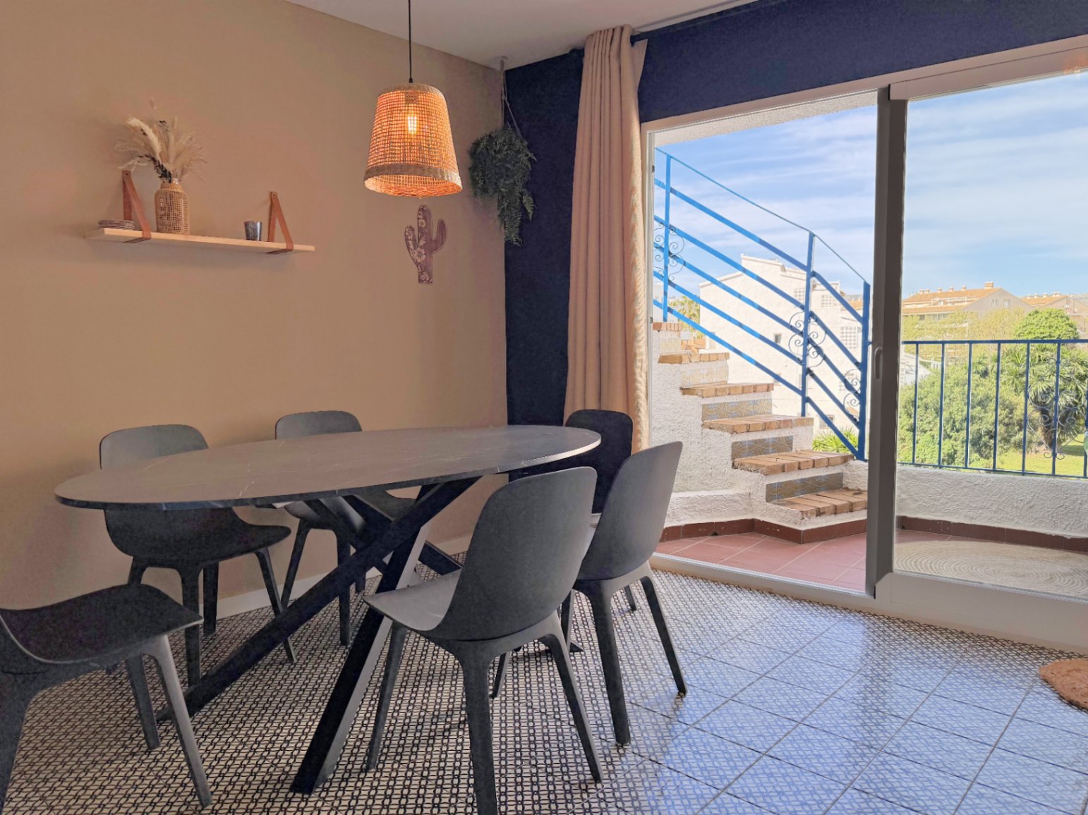 Dining room featuring a black oval table and access to an outdoor terrace with blue stairs.