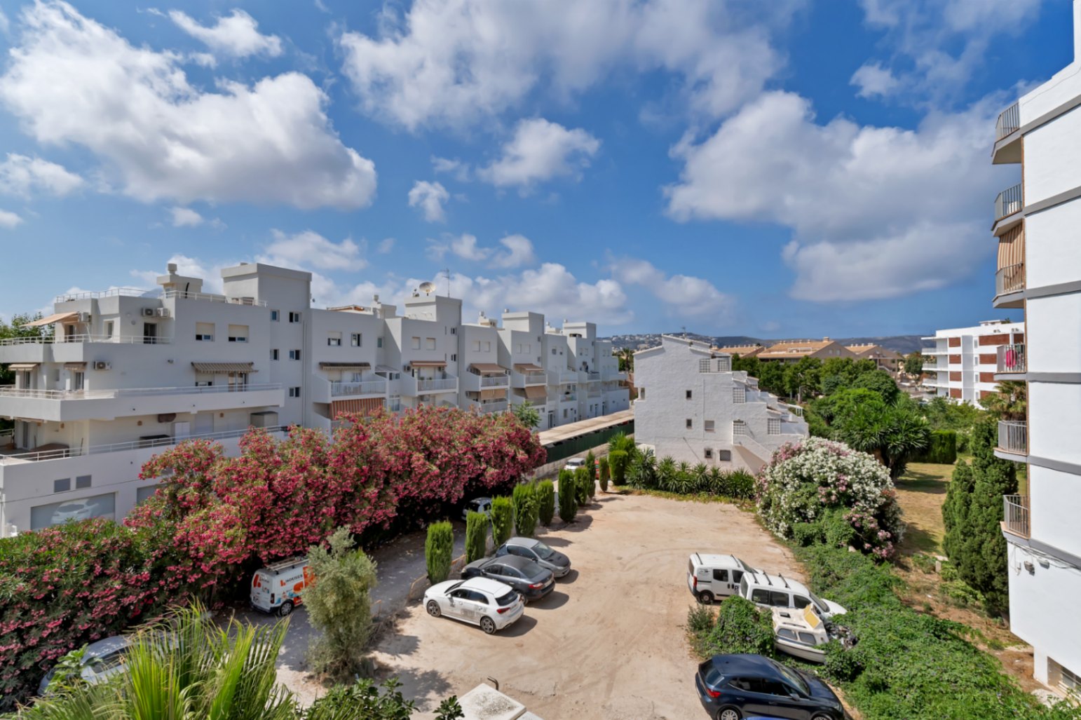Elevated view of community parking, surrounded by white buildings and lush greenery in Jávea.
