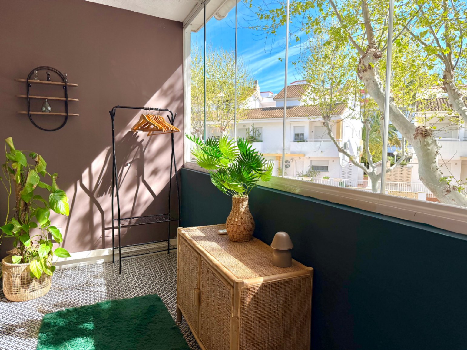 Interior detail with brown and green walls, wicker furniture, and street views from the glassed-in terrace.